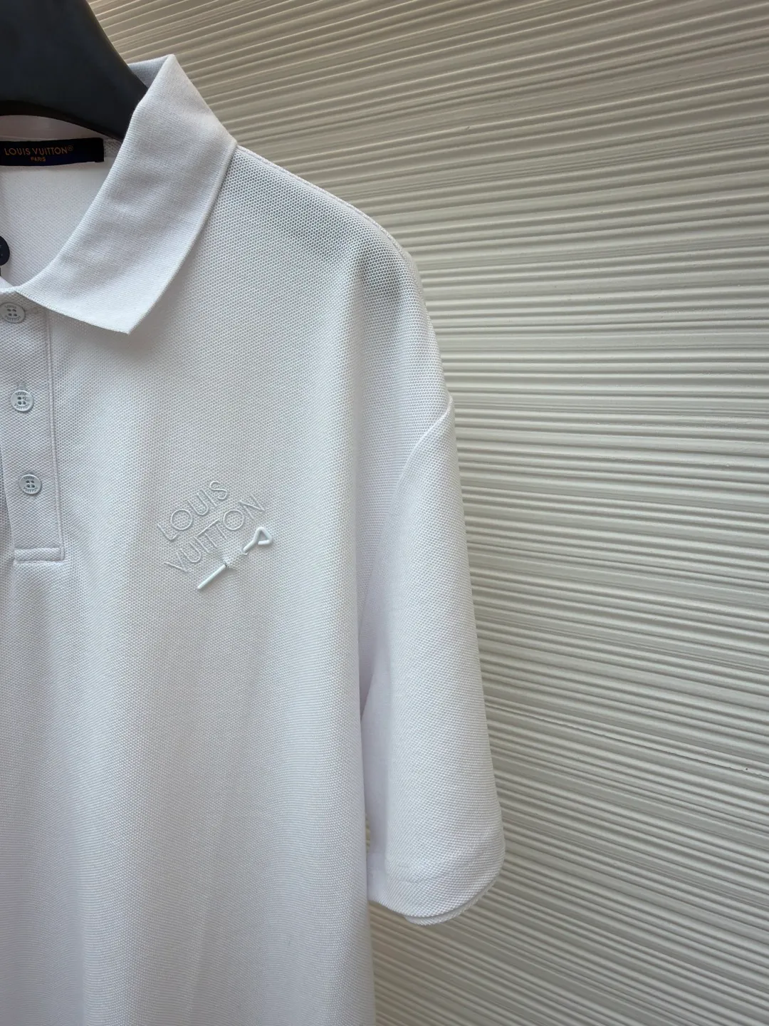 LOUIS VUITTON pin embroidered polo shirt ●Original version: Purchased and developed for 6500 ●Item number: 1681204-A35 ●Fabric: pique cotton fabric ●Technology: embroidery production ●Color: white ●Version: fitted version ●Weight: about 305 grams ●Size: XS-S-M-L ●Description: The fabric is made of customized 6-corner piqué cotton, with unique shape and texture, which is breathable and comfortable, not easy to deform and has greatly increased durability; the flat-knit thread dyeing for the neckline ensures that the color of the neckline perfectly matches the overall tone of the clothes. The flat-knit thread production process makes the neckline highly elastic and fits the neck without feeling constrained when worn; a keyhole is specially made under the embroidery, and custom-made pin accessories are strung together as decorative highlights to add a sense of fashion and uniqueness to the clothes. The overall wiring is straight and delicate, the fabric is comfortable and soft, and the color is consistent without color difference. It can be matched with the same style to create a fashionable look and control various occasions. Customized accessories, complete with three standards, same style for men and women!